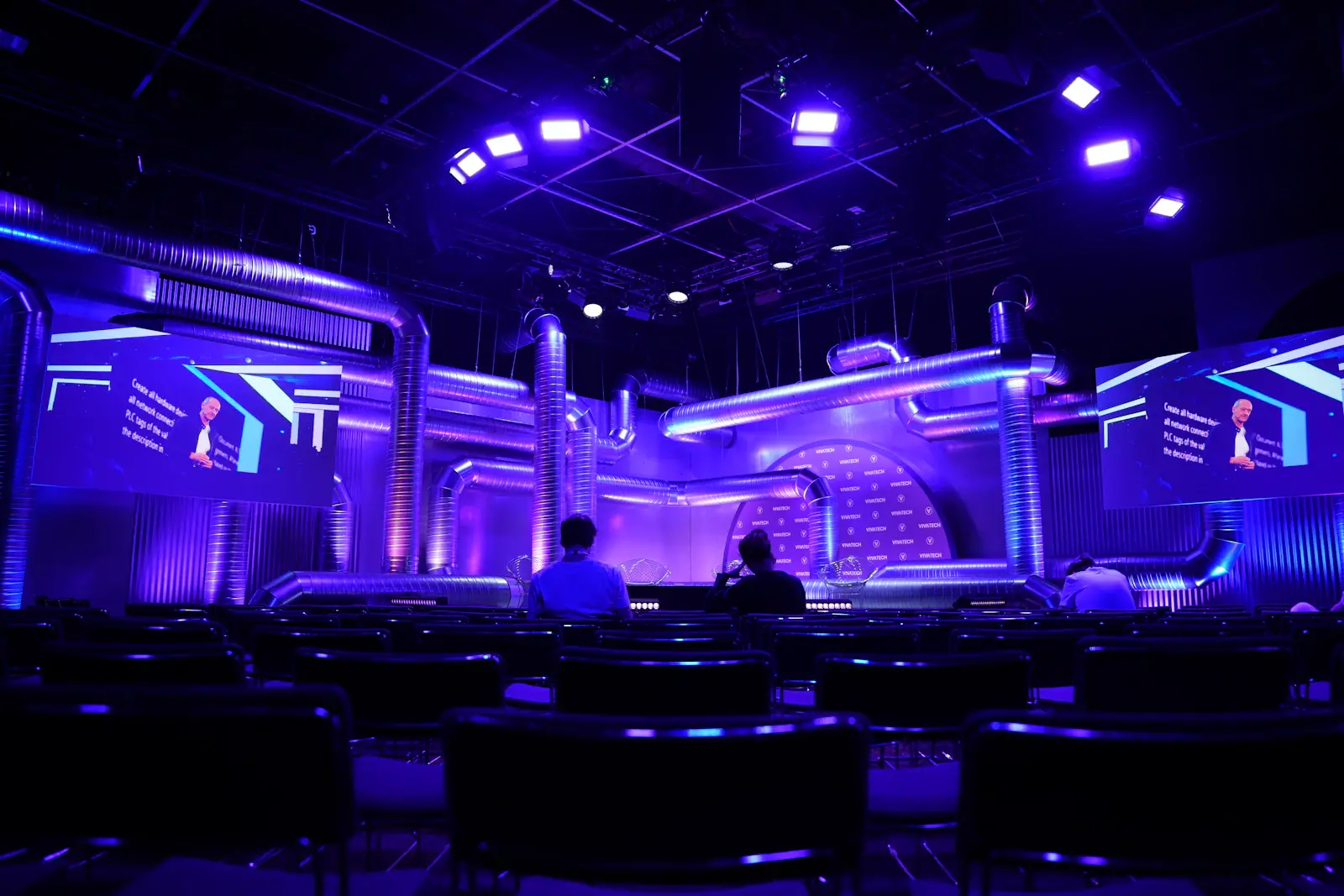 Corporate event stage with purple lighting and seated audience